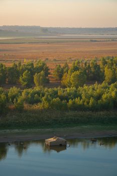 Wooden fishermen house inside water on Guadiana river between Spain and Portugal with beautiful tree landscape at sunrise