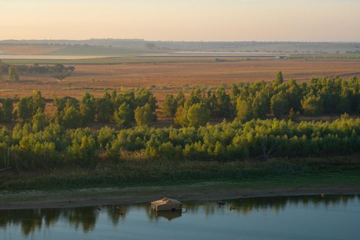 Wooden fishermen house inside water on Guadiana river between Spain and Portugal with beautiful tree landscape at sunrise