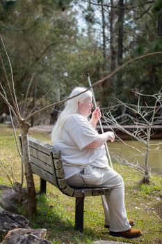 Blind woman sitting on a bench near a pond