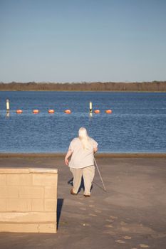 Blind woman walking past a tan brick wall toward a swimming area