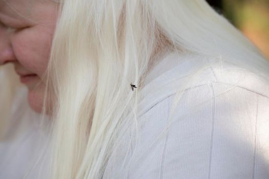 Woman with a black flying bug in her white hair