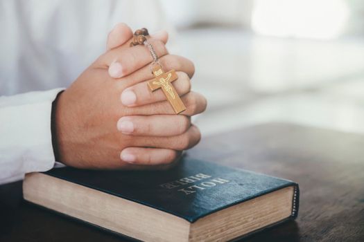 Religion, Christianity, Praying. Man praying, hands clasped together on her Bible.