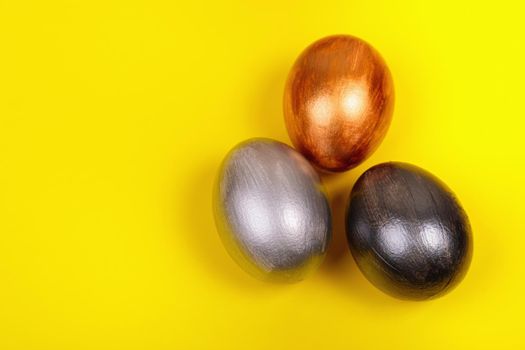 Easter. Multi-colored eggs on a uniform yellow background with place for text. View from above