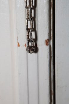 Old door chain hanging on a door frame