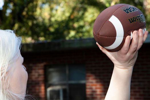 Albino woman throwing a football in a yard game