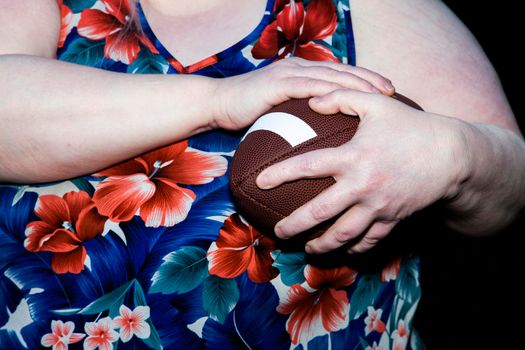 Woman protects a football as she prepares to run with it