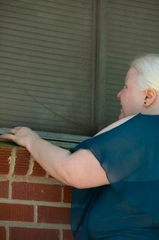 Legally blind woman checking a window for damage