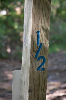 Wooden post in nature marked as one-half (1/2) in blue numerals