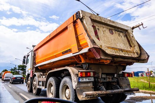 Traffic with road view through car front window, Dirty Schmitz Cargobull tipper trailer truck in traffic. Bucharest, Romania, 2020