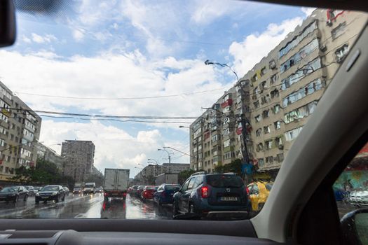 Traffic in cloudy rainy day with road view through car front window in Bucharest, Romania, 2020