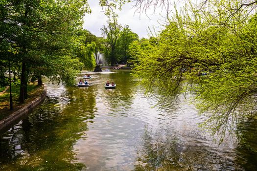 People on pedal boat on lake in Cismigiu Park, Bucharest, Romania, 2020. People walking, having fun, enjoying outdoor in park after quarantine or restrictions of coronavirus.