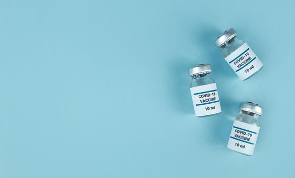 Medicine bottles with covid 19 vaccine on blue background with copy space.