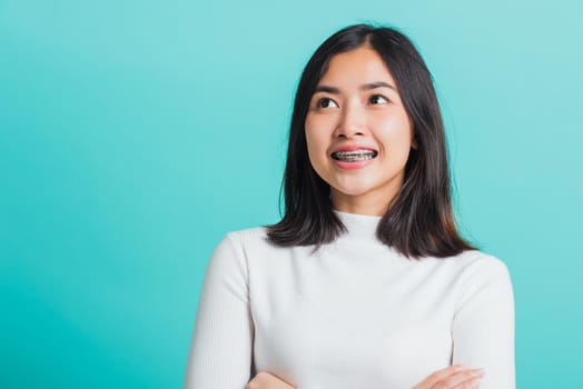 Young beautiful Asian woman smiling with crossed arms, Portrait of positive confident female stand cross one's arm, studio shot isolated on a blue background