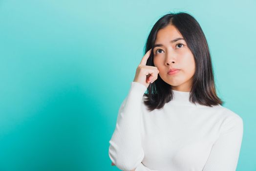 Young beautiful Asian woman hand near the face and thinking, Portrait  female touch brow tail dream dreamy having doubts, studio shot isolated on a blue background