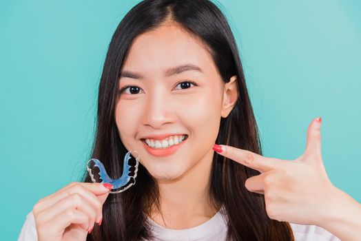 Female hold teeth retaining tools after removable braces, Portrait young Asian beautiful woman smiling pointing with finger silicone orthodontic retainers for teeth, Orthodontics dental care concept
