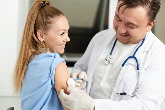 male doctor in a white coat injects a vaccine into the patient's hand. High quality photo