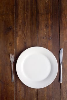 White plate on wooden background, copy space