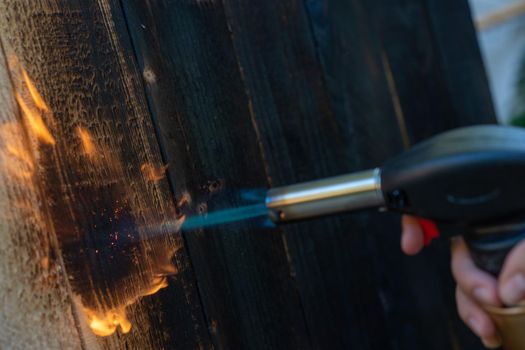 Professional carpenter using old traditional japanese technique. Burning wood planks with gas burner. DIY process.