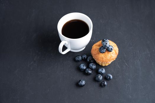 Blueberry antioxidant organic superfood and sweet muffin with cup of coffe Concept for healthy eating and dieting nutrition Top view on dark black background