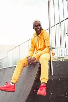 African-american smiling black man yellow hoodie outside Happy emotional afro model guy sitting skate park summer day Free space Positive emotions