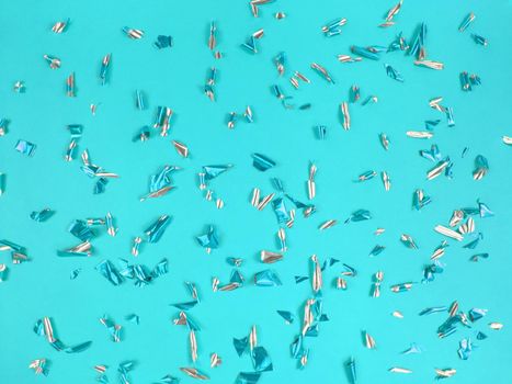 Confetti foil pieces on a blue background. Abstract festive backdrop.