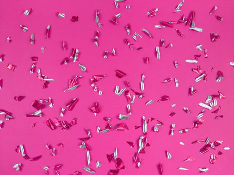Confetti foil pieces on a pink background. Abstract festive backdrop.