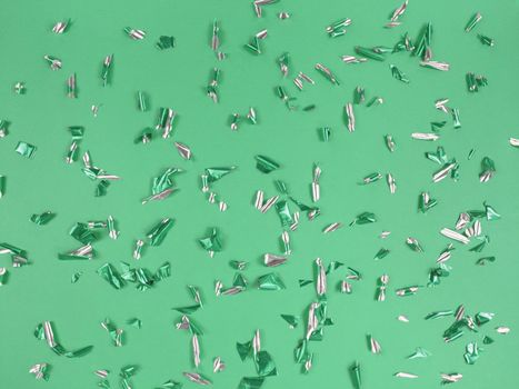 Confetti foil pieces on a green background. Abstract festive backdrop.