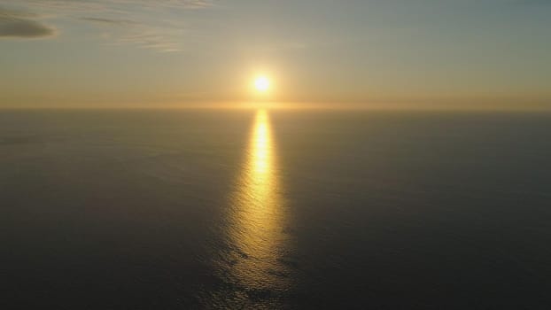 Aerial view of sunshine with glare on the surface water at sunset. Orange sunset over the sea. Philippines, Luzon. Travel concept.