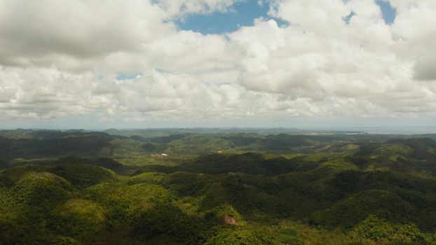 Tropical island covered with green rainforest with hills and mountains. Cloudy landscape over the island. Siargao,Philippines