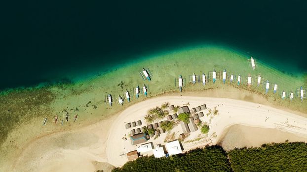 Tropical island and sandy beach with tourists surrounded by coral reef and blue sea in honda bay, aerial view. Island with sand bar and coral reef. starfish island. Summer and travel vacation concept, Philippines, Palawan