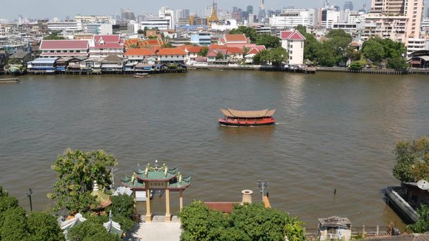 Oriental boat floating on river in Krungthep city. Modern transport vessel floating on calm Chao Praya river on sunny day in Bangkok near chinatown. Panorama.