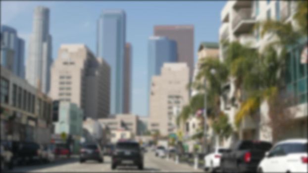 Driving on downtown streets of Los Angeles, California USA. Defocused view from car thru glass windshield on driveway. Blurred road with vehicles in Hollywood. Camera inside auto, LA city aesthetic.