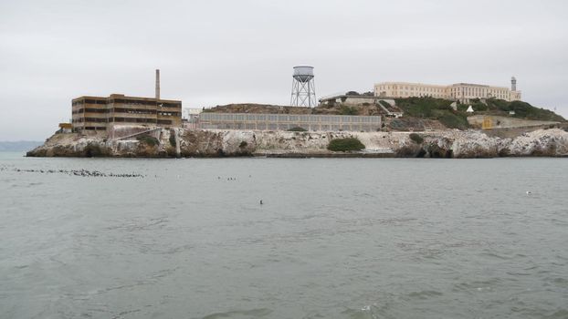 Alcatraz island in San Francisco Bay, California USA. Federal prison for gangsters on rock, foggy weather. Historic jail, cliff in misty cloudy harbor. Gaol for punishment and imprisonment for crime.