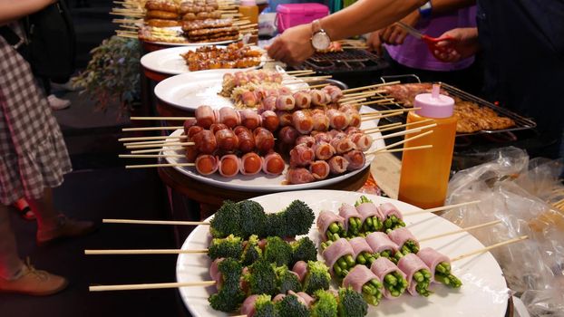 Traditional Asian night street food market in Thailand. Barbecue meatballs and other exotic delicious snacks for sail. Ready to eat food.