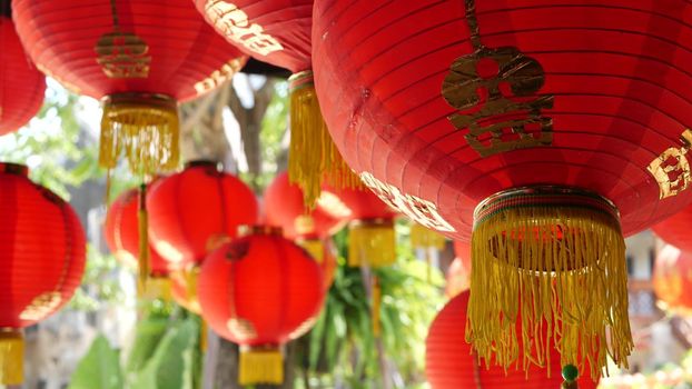 Paper lanterns on shabby building. Red paper lanterns hanging on ceiling of weathered concrete temple building on sunny day in oriental country. traditional decoration.