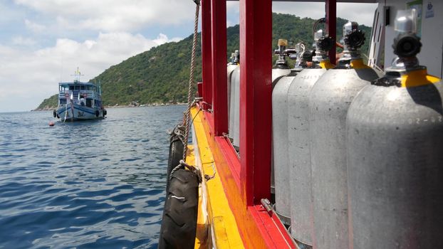 Row of oxygen tanks and diving equipment placed on modern boat in rippling ocean near Koh Tao resort, Thailand. Concept of tourist sports extreme entertainment, adventure and new experience