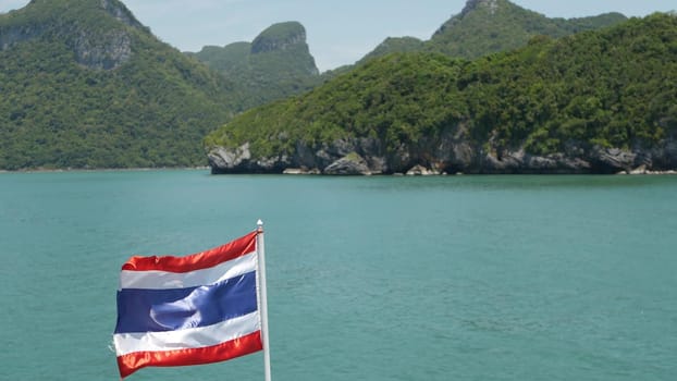 Group of Islands in ocean at Ang Thong National Marine Park. Archipelago in the Gulf of Thailand. Idyllic turquoise sea natural background with copy space. Waving flag as national symbol on the boat