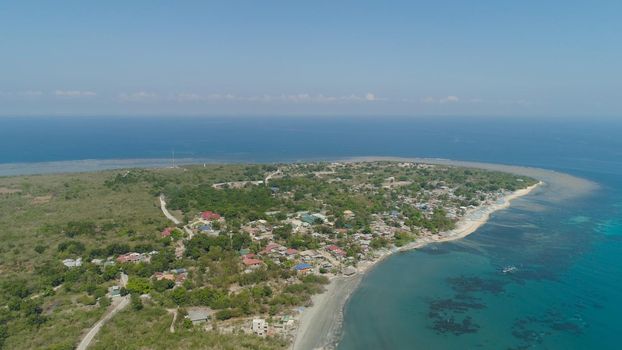 Tropical island with sandy beach, palm trees. Aerial view of coast island Pinget with colorful reef. Seascape, ocean and beautiful beach. Philippines, Luzon. Travel concept.