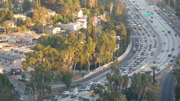 Busy rush hour intercity highway in metropolis, Los Angeles, California USA. Urban traffic jam on road in sunlight. Aerial view of cars on multiple lane driveway. Freeway with automobiles in LA city.