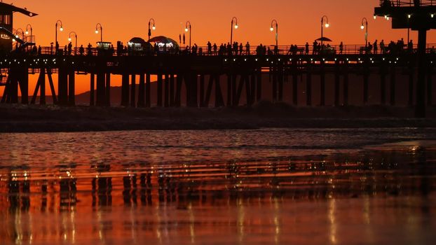 California summertime beach aesthetic, golden sunset. Vivid sky over pacific ocean waves. Santa Monica popular resort, Los Angeles CA USA. Famous pier against atmospheric moody evening sundown in LA.