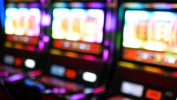 Defocused slot machines glow in casino on fabulous Las Vegas Strip, USA. Blurred gambling jackpot slots in hotel near Fremont street. Illuminated neon fruit machine for risk money playing and betting.