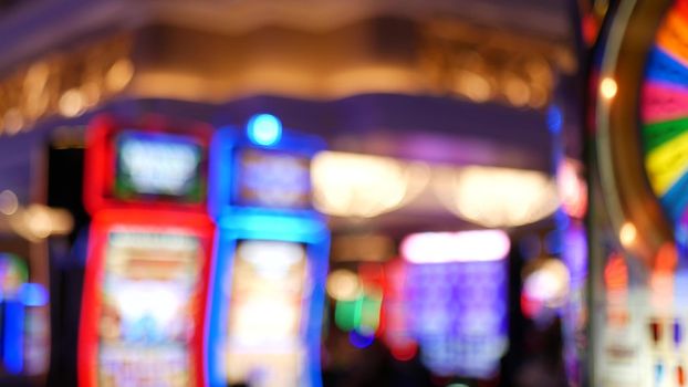 Defocused slot machines glow in casino on fabulous Las Vegas Strip, USA. Blurred gambling jackpot slots in hotel near Fremont street. Illuminated neon fruit machine for risk money playing and betting.