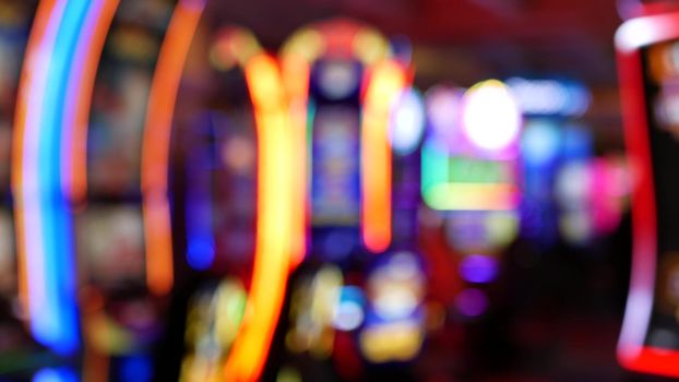 Defocused slot machines glow in casino on fabulous Las Vegas Strip, USA. Blurred gambling jackpot slots in hotel near Fremont street. Illuminated neon fruit machine for risk money playing and betting.