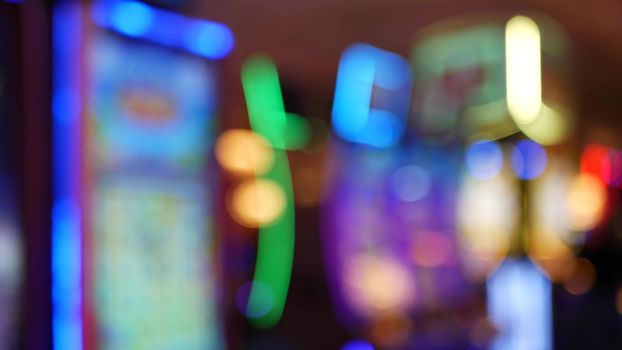 Defocused slot machines glow in casino on fabulous Las Vegas Strip, USA. Blurred gambling jackpot slots in hotel near Fremont street. Illuminated neon fruit machine for risk money playing and betting.