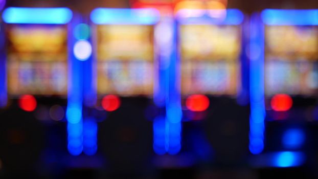 Defocused slot machines glow in casino on fabulous Las Vegas Strip, USA. Blurred gambling jackpot slots in hotel near Fremont street. Illuminated neon fruit machine for risk money playing and betting.