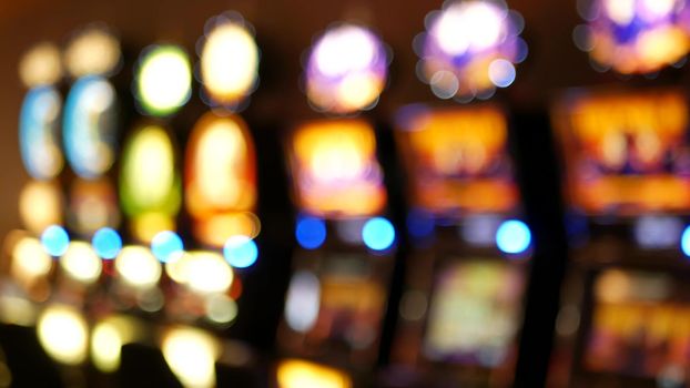 Defocused slot machines glow in casino on fabulous Las Vegas Strip, USA. Blurred gambling jackpot slots in hotel near Fremont street. Illuminated neon fruit machine for risk money playing and betting.