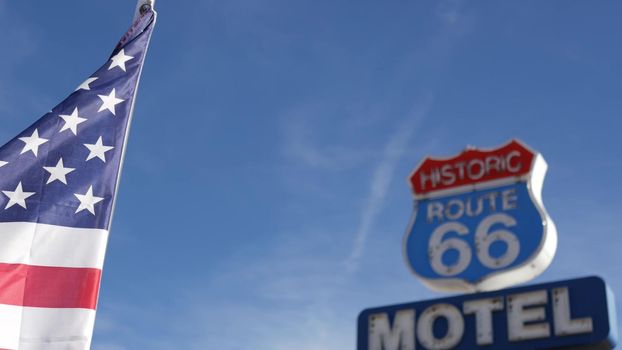 Motel retro sign on historic route 66 famous travel destination, vintage symbol of road trip in USA. Iconic lodging signboard in Arizona desert. Old-fashioned neon signage. National state flag waving.