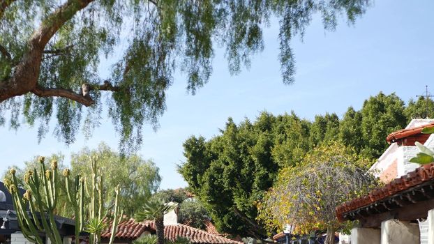 Mexican colonial style suburban, hispanic house exterior, green lush garden, San Diego, California USA. Mediterranean terracotta ceramic clay tile on roof. Rustic spanish tiled rooftop. Rural details.