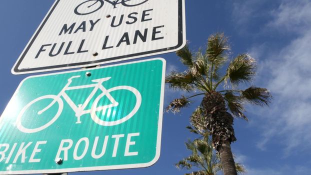 Bike Route green road sign in California, USA. Bicycle lane singpost. Bikeway in Oceanside pacific tourist resort. Cycleway signboard and palm. Healthy lifestyle, recreation and safety cycling symbol.