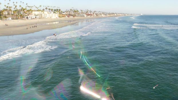 Blowing soap bubbles on ocean pier in California, blurred summertime background. Creative romantic metaphor, concept of dreaming happiness and magic. Abstract symbol of childhood, fantasy, freedom.